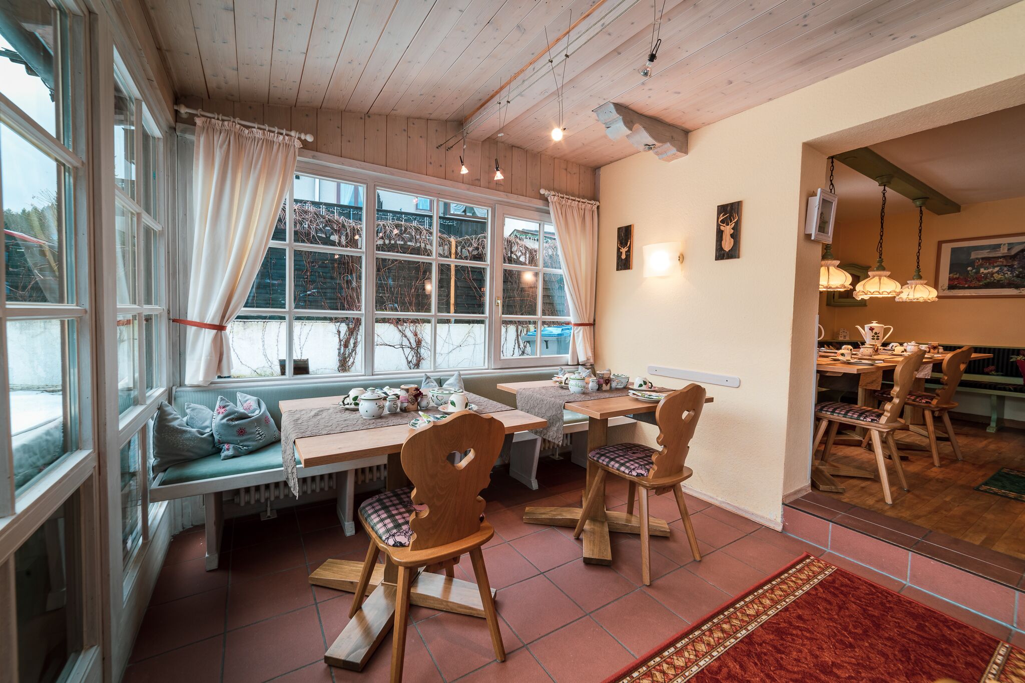 A cozy dining area with wooden furniture, a bench, and a view of the outside.