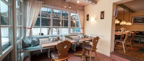 A cozy dining area with wooden furniture, a bench, and a view of the outside.