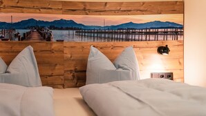 A bedroom with two beds, a wooden headboard, and a wall-mounted lamp. - Hotel Garni Landhaus Traunbachhäusl (Ruhpolding)