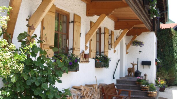 A traditional chalet with a wooden balcony, wooden beams, and flower boxes. - Hotel Garni Landhaus Traunbachhäusl (Ruhpolding)