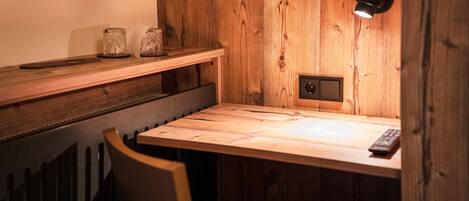 Una mesa de comedor de madera con un control remoto, una lámpara de pared y dos recipientes de vidrio en un estante superior.