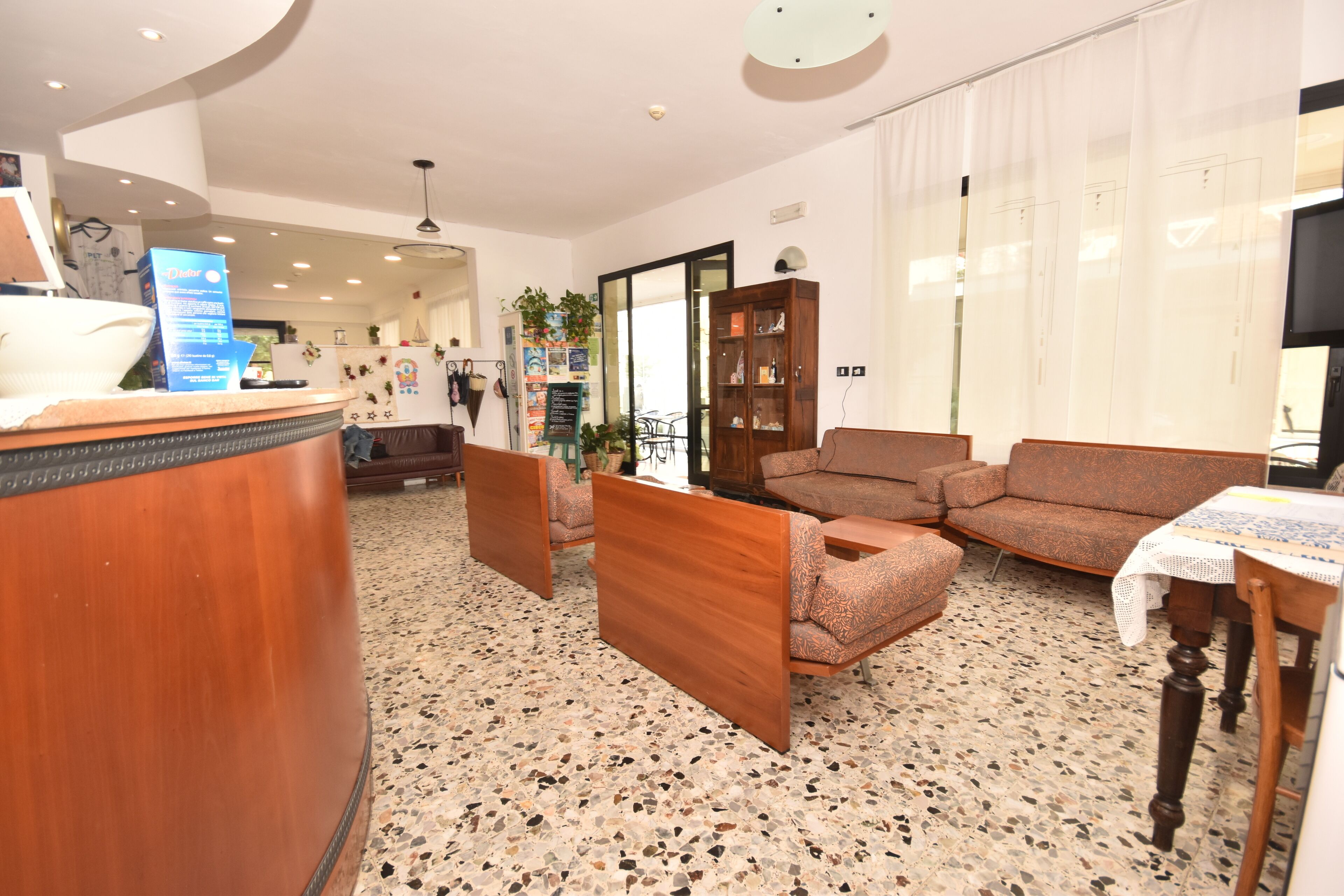 A hotel lobby with a reception desk, seating area, and a large window.