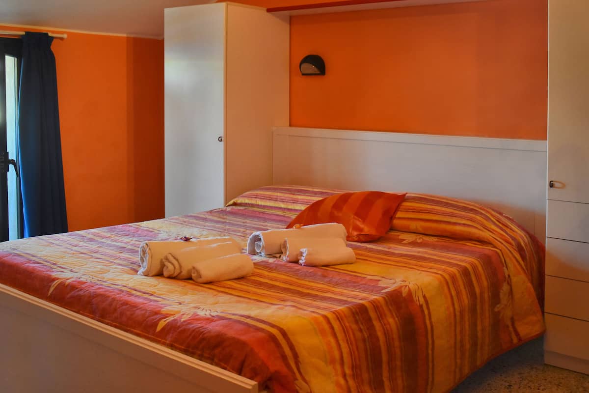 A hotel room with a bed, a wardrobe, and a wall-mounted light fixture.