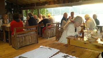 A rustic wooden interior with wooden benches and tables, a view of greenery outside, and a casual dining atmosphere.