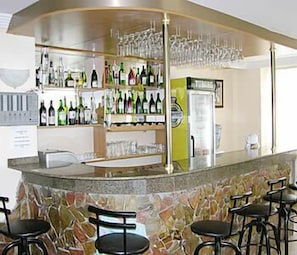 A bar area with a stone counter, multiple shelves of bottles, and bar stools. - Aquarium Hotel (Istanbul)