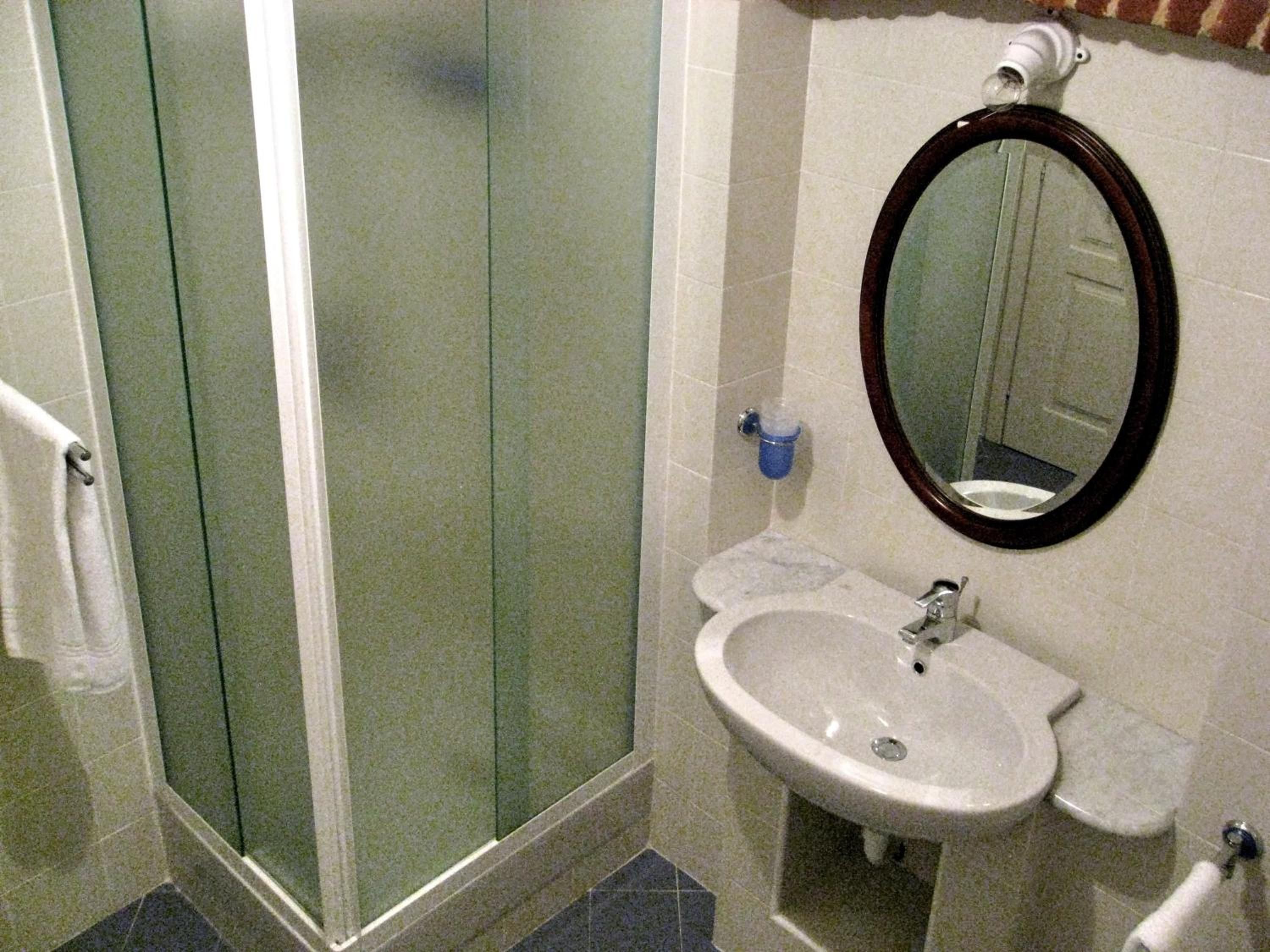 A bathroom with a glass shower enclosure, a sink with a mirror, and a toilet.
