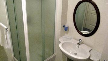 A bathroom with a glass shower enclosure, a sink with a mirror, and a toilet.