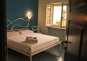 A bed with a headboard, a bedside table, and a window with curtains. - Agriturismo Cascina Ponchietta (Monta)