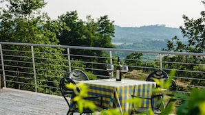 A table set outdoors with a checkered tablecloth, surrounded by chairs, and a bottle of wine on the table. - Agriturismo Cascina Ponchietta (Monta)