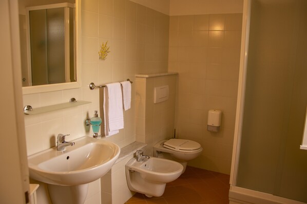 A bathroom with a sink, bidet, toilet, and a shower area. - Agriturismo Cascina Ponchietta (Monta)