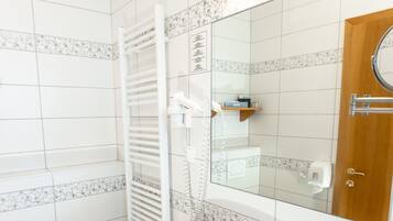 Une salle de bain moderne équipée d’un bidet, d’un lavabo et d’un miroir.