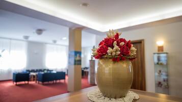 A vase with red and white flowers on a wooden table in a room with a red carpet and a white ceiling.