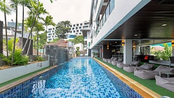 Una piscina al aire libre, sillones reclinables de piscina