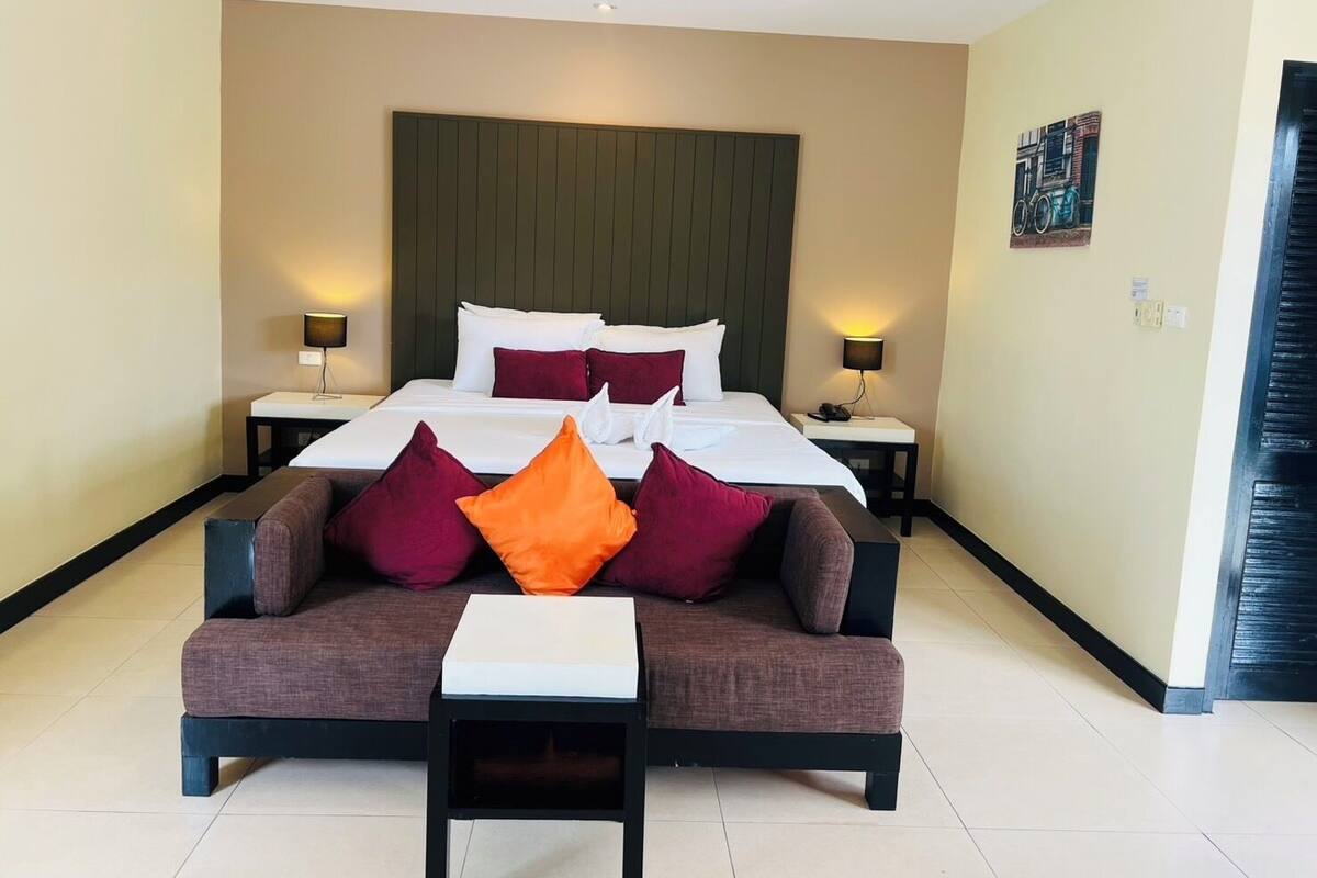 Une chambre d’hôtel avec un grand lit, deux tables de chevet, un canapé et une petite table.