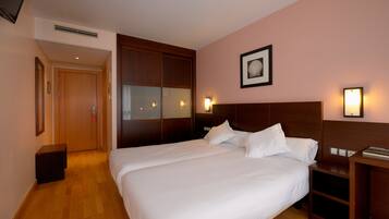 A hotel room with a large bed, wooden wardrobe, bedside tables, and a framed picture on the wall.