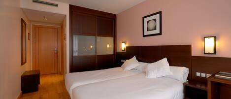 Habitación de hotel con una cama grande, armario de madera, mesitas de noche y un cuadro enmarcado en la pared.