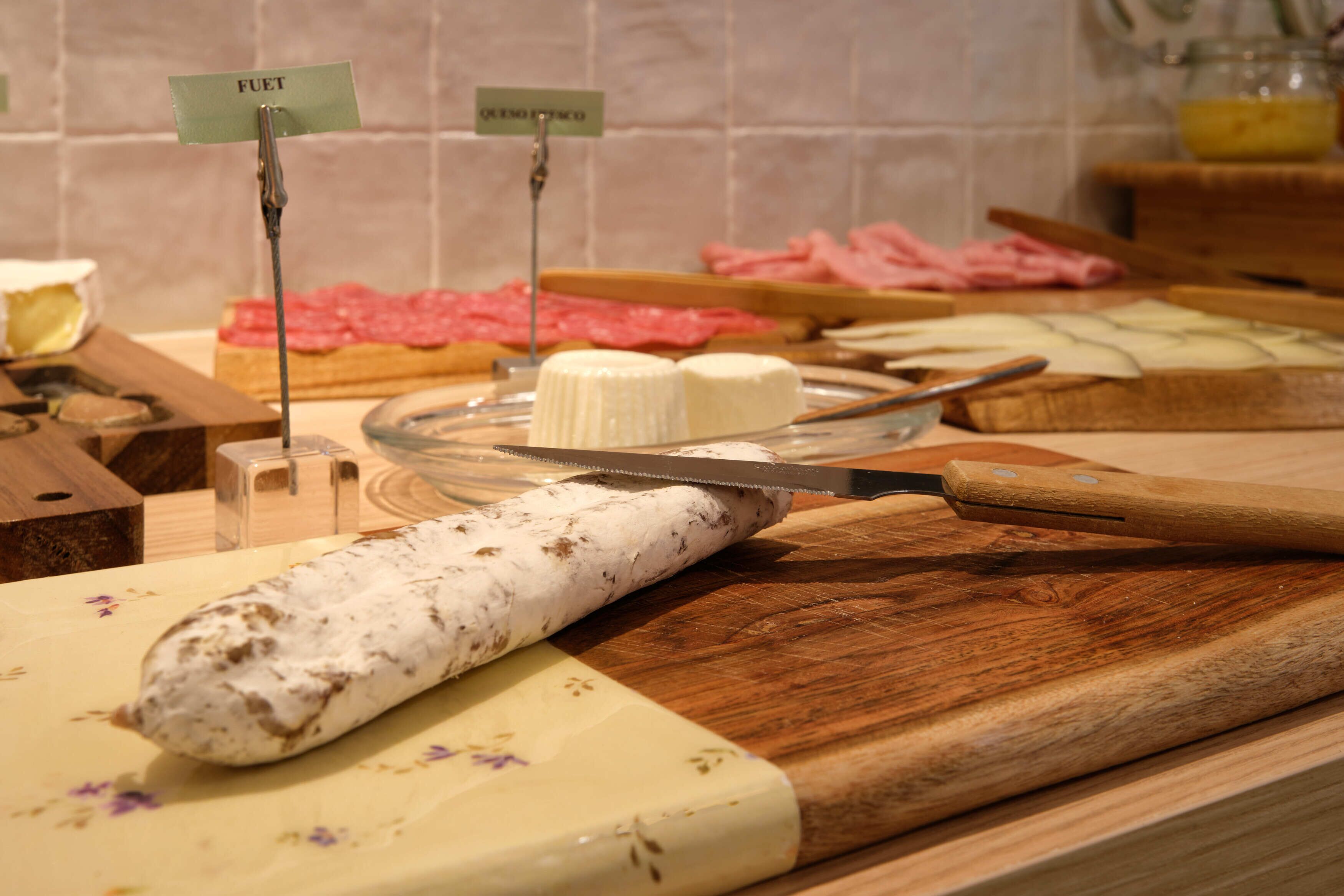 A variety of cheeses and meats on a counter with labels.