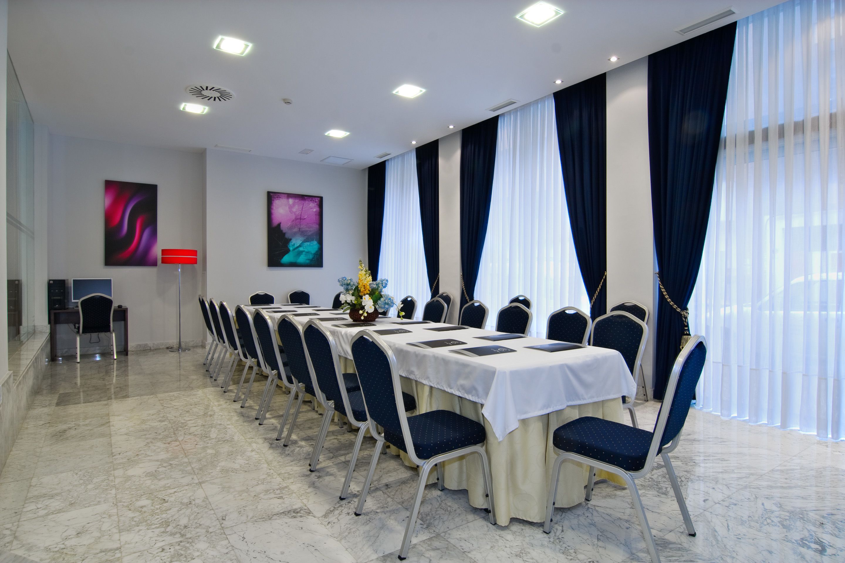 A conference room with a long table, chairs, and a white tablecloth.