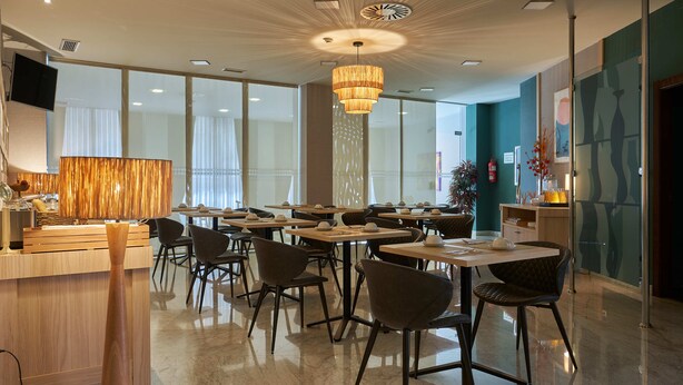 Un restaurante moderno con una lámpara central, varias mesas y sillas dispuestas para comer.