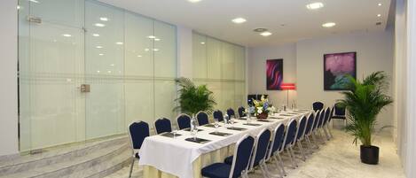 A conference room with a long table, chairs, and potted plants.