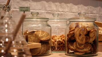 Trois bocaux en verre, étiquetés, sont posés sur une surface en bois et contiennent différents types de produits de boulangerie.