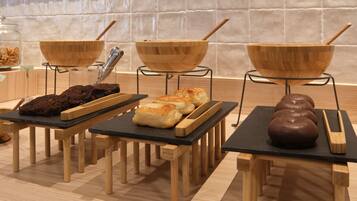 A kitchen area with wooden tables displaying baked goods and a chocolate sculpture.