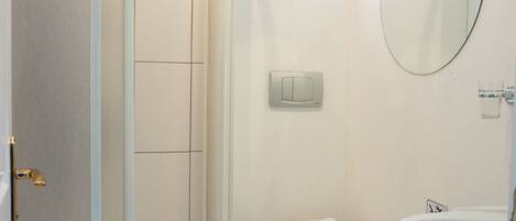 Een badkamer met douche, toilet en bad.