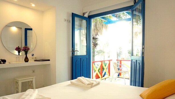 A hotel room with a bed, a bathroom with a mirror and a shelf, and a balcony with a blue railing. - Su Hotel (Bodrum)