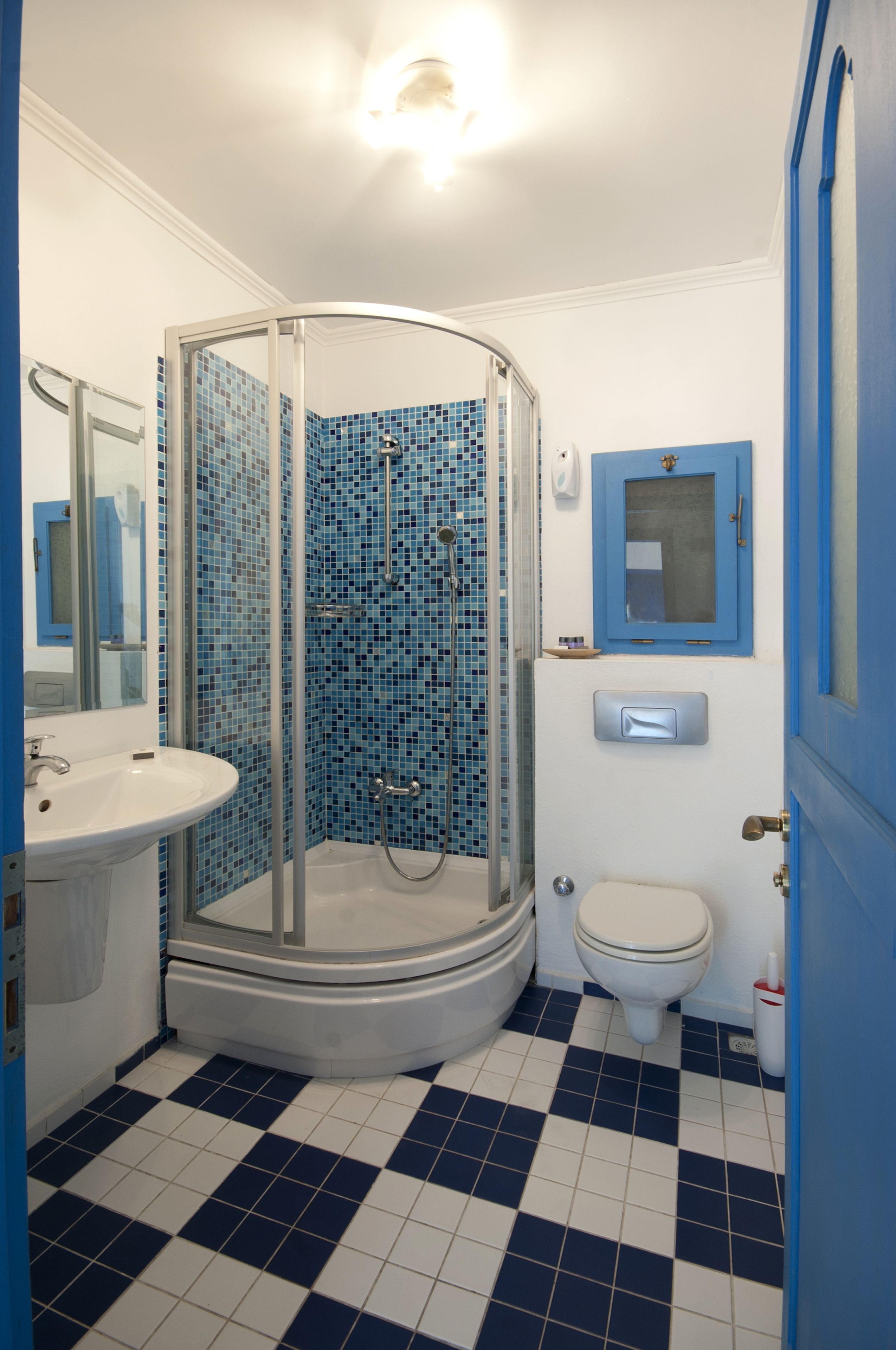 Un baño con cabina de ducha de vidrio, lavabo, inodoro y espejo.