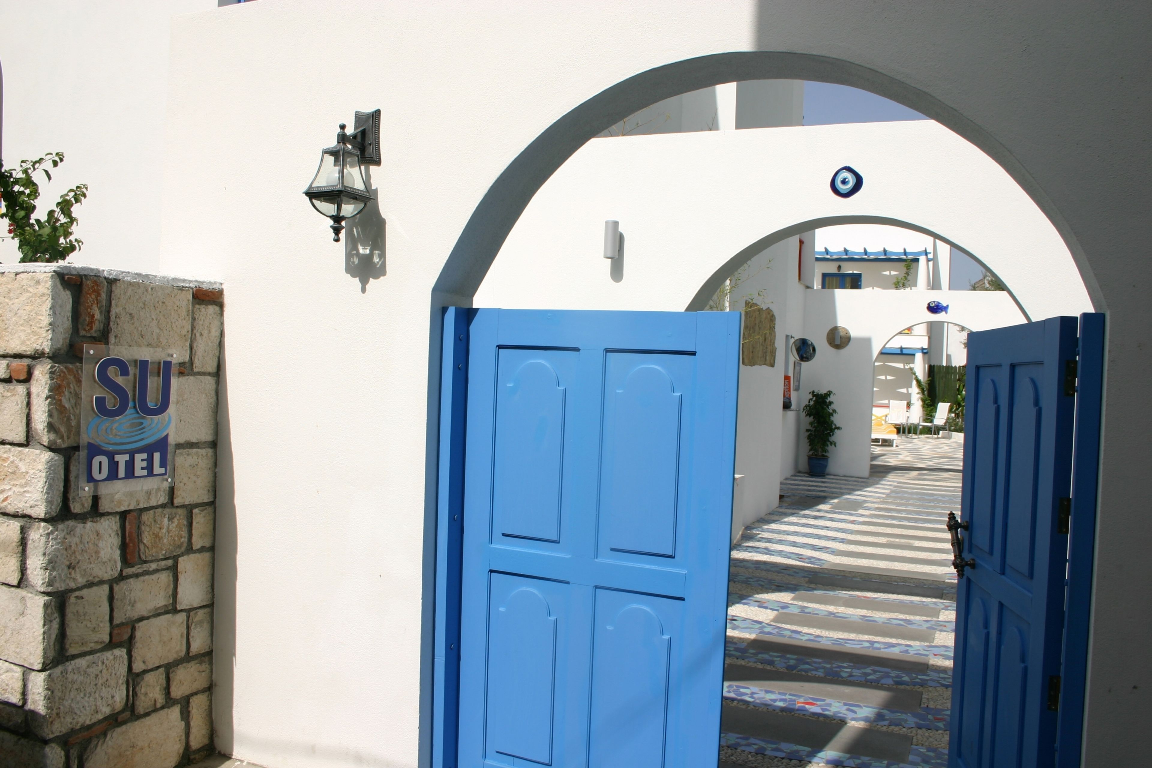 Un arco de entrada a un hotel, con una puerta azul y un letrero que dice "SU HOTEL".
