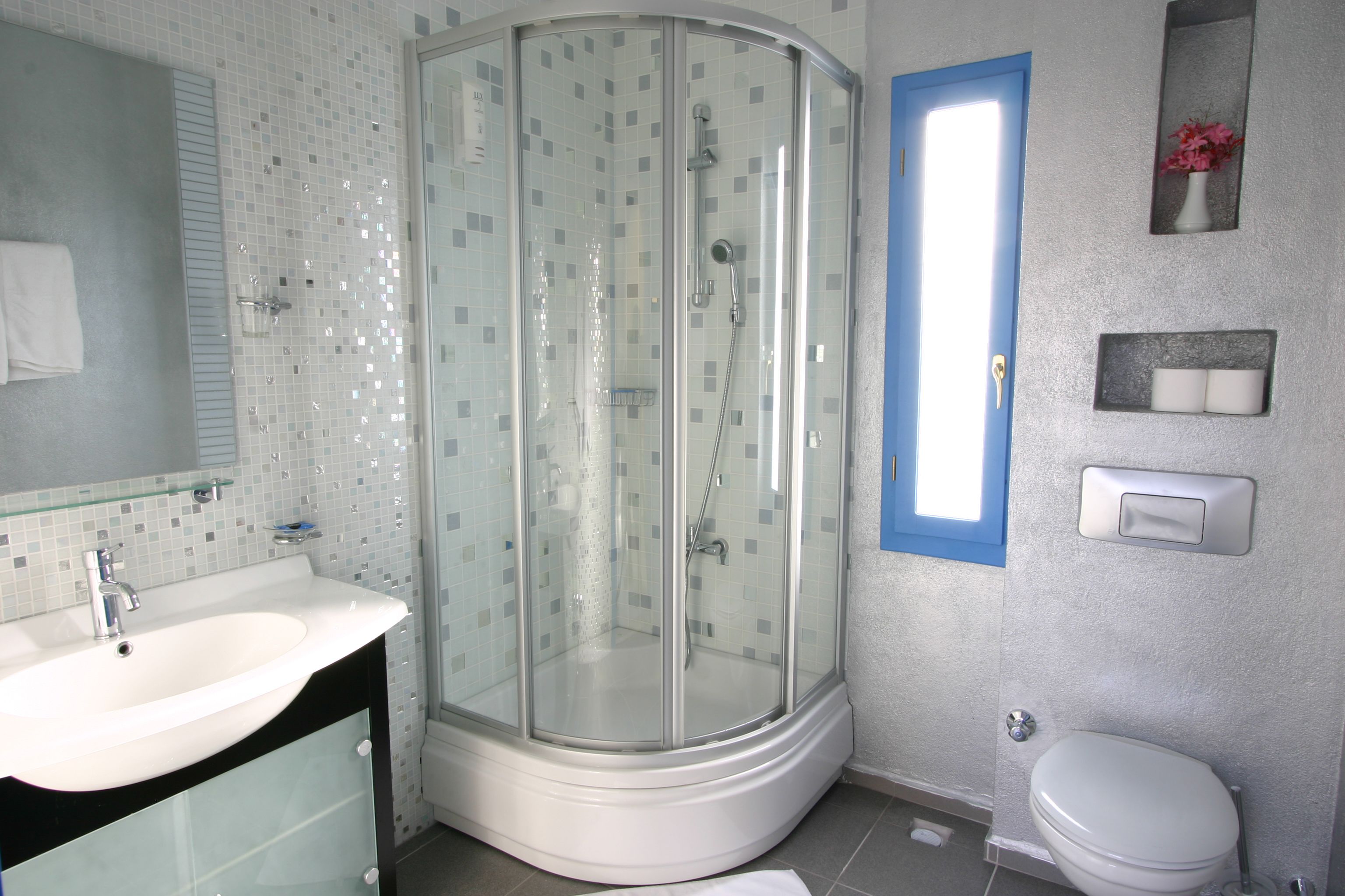 Un baño con cabina de ducha de vidrio, un lavabo blanco y un inodoro.