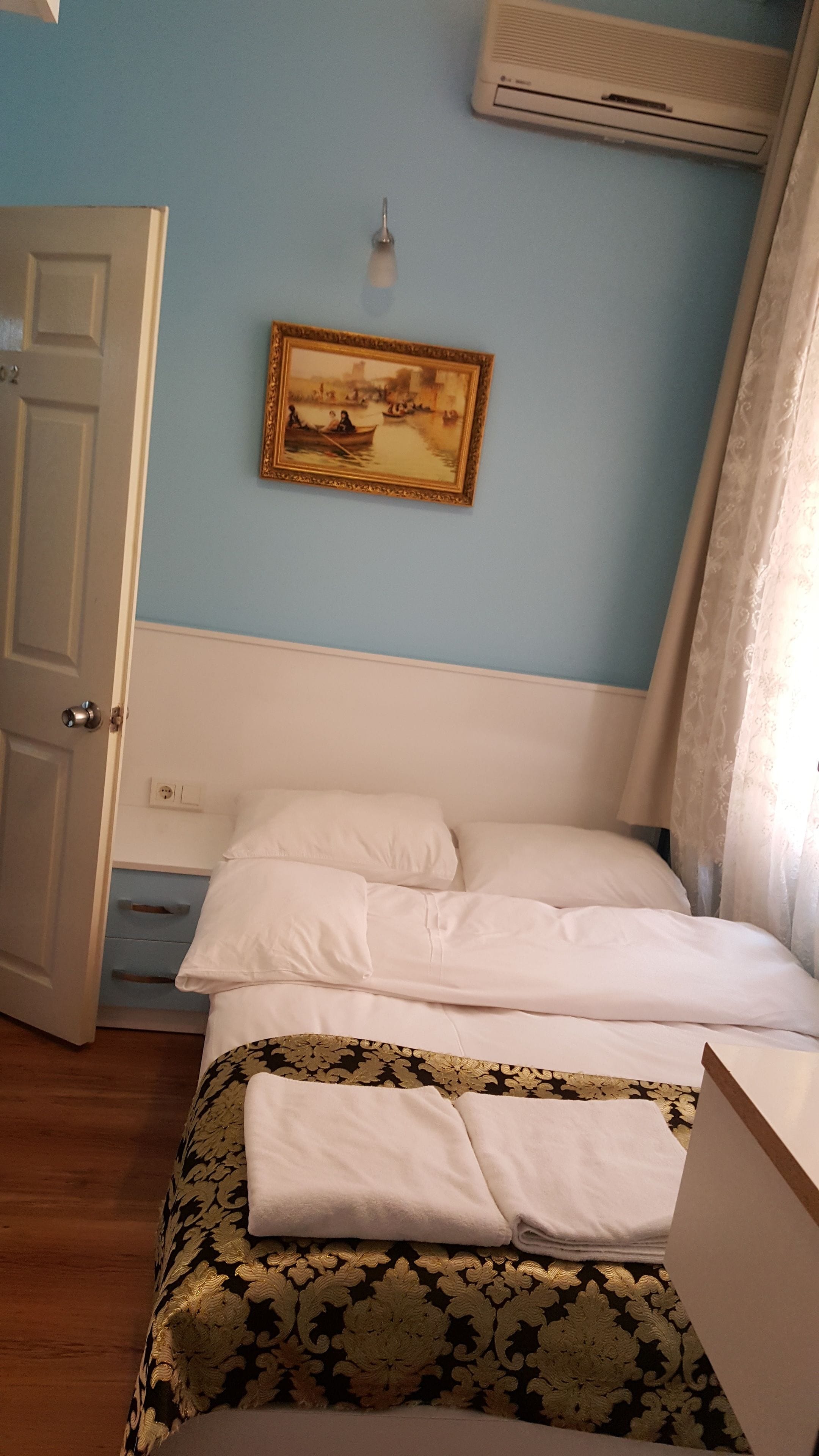Ein Schlafzimmer mit einem Bett, einem Bild an der Wand, einer Tür und einer Klimaanlage.