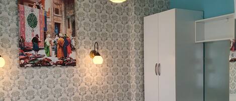 A bedroom with a bed, a wardrobe, a nightstand, and a wall-mounted lamp.
