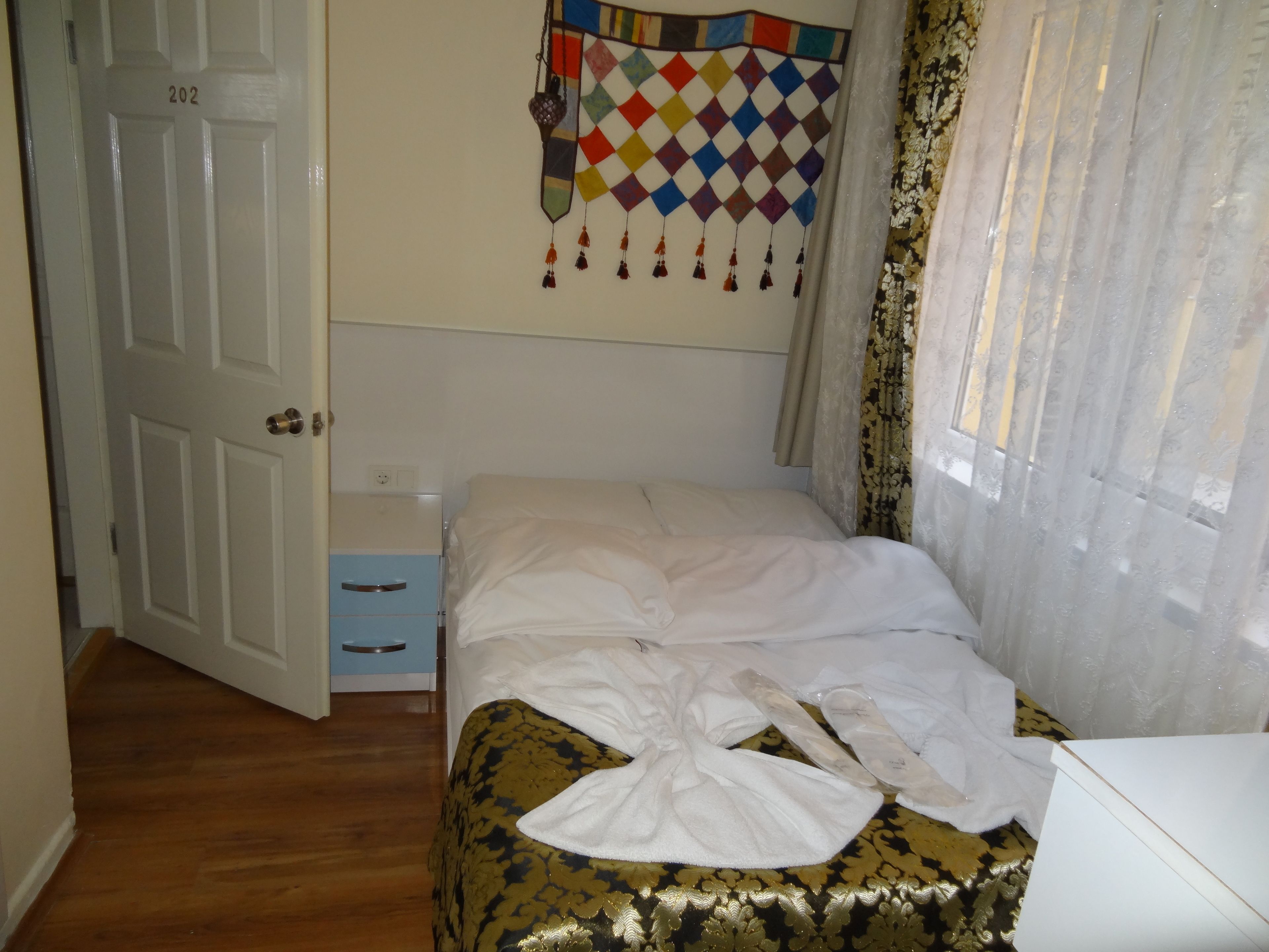 Un dormitorio con cama, una puerta, un aparador y un adorno en la pared.