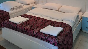 Quarto de hotel com duas camas, papel de parede estampado e luminárias fixadas na parede.