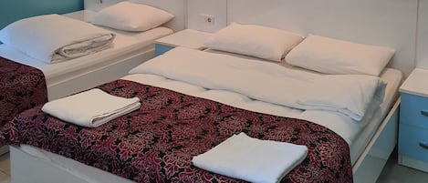 A hotel room with two beds, a patterned wallpaper, and wall-mounted lights.