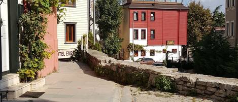 Une ruelle étroite pavée, bordée de bâtiments des deux côtés, dont un hôtel sur lequel on peut lire l’inscription « HÔTEL EMRS ».