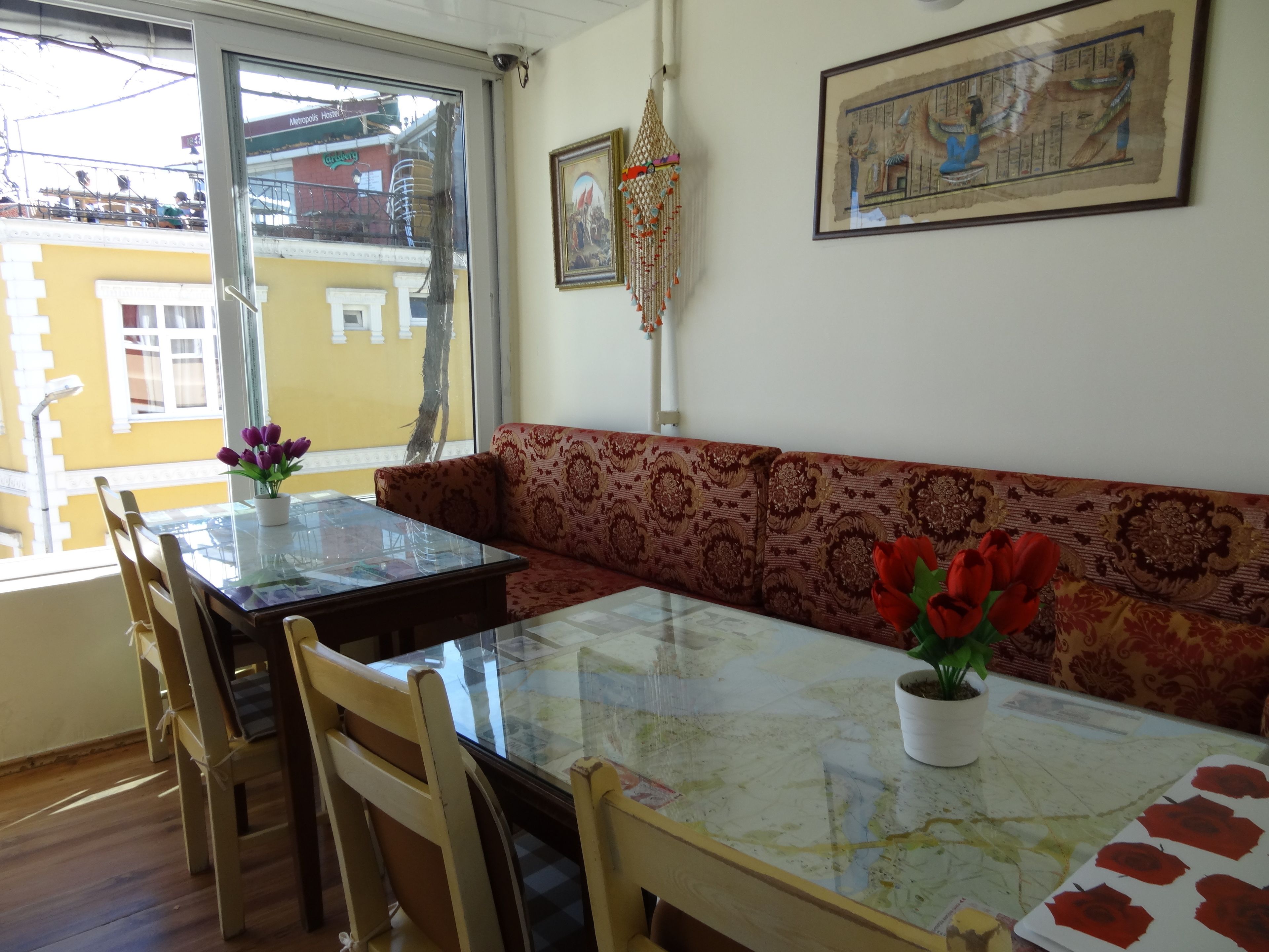 A dining area with a glass table, wooden chairs, and a patterned sofa.