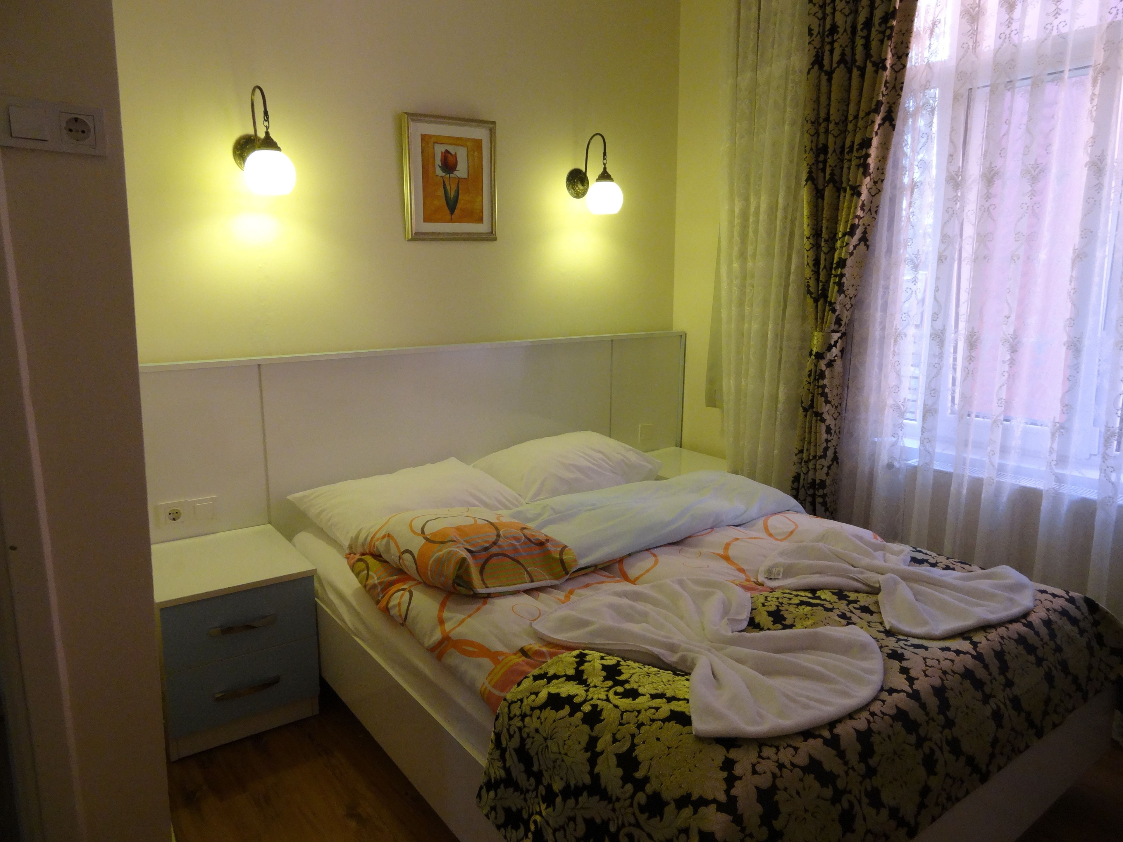 Una camera da letto con un letto, comodini, un quadro appeso al muro e una finestra con tende.