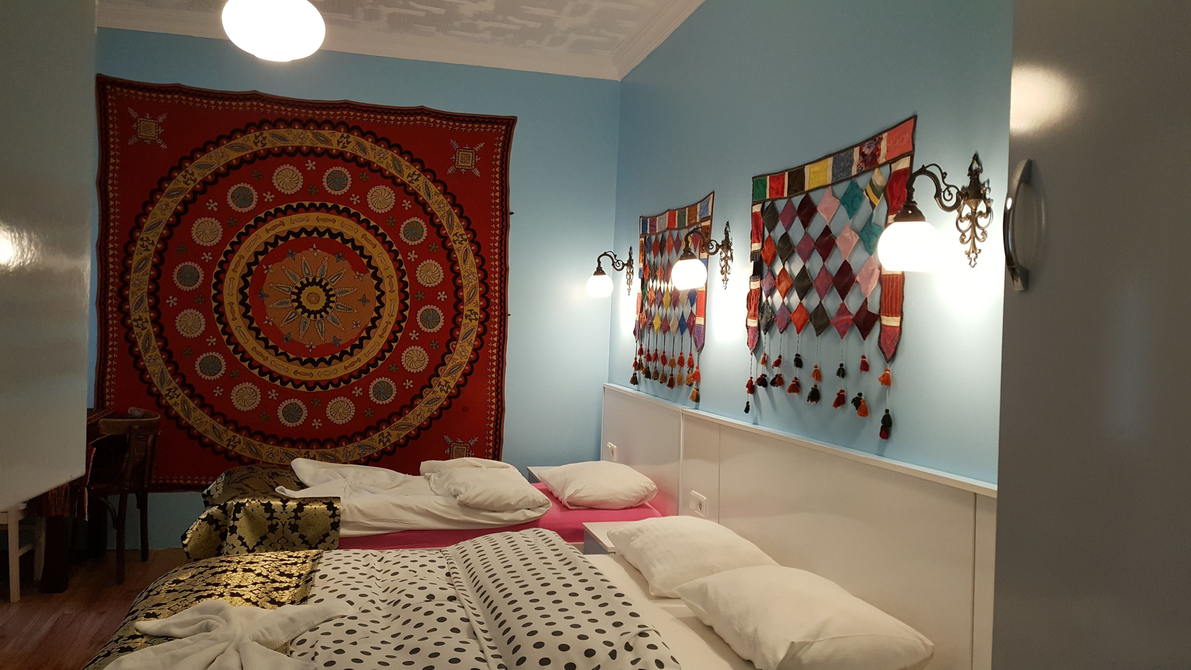 A bedroom with a bed, a large tapestry, and wall decorations.