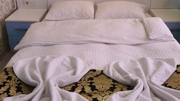 A neatly made bed with white linens, a headboard, and two bedside lamps.