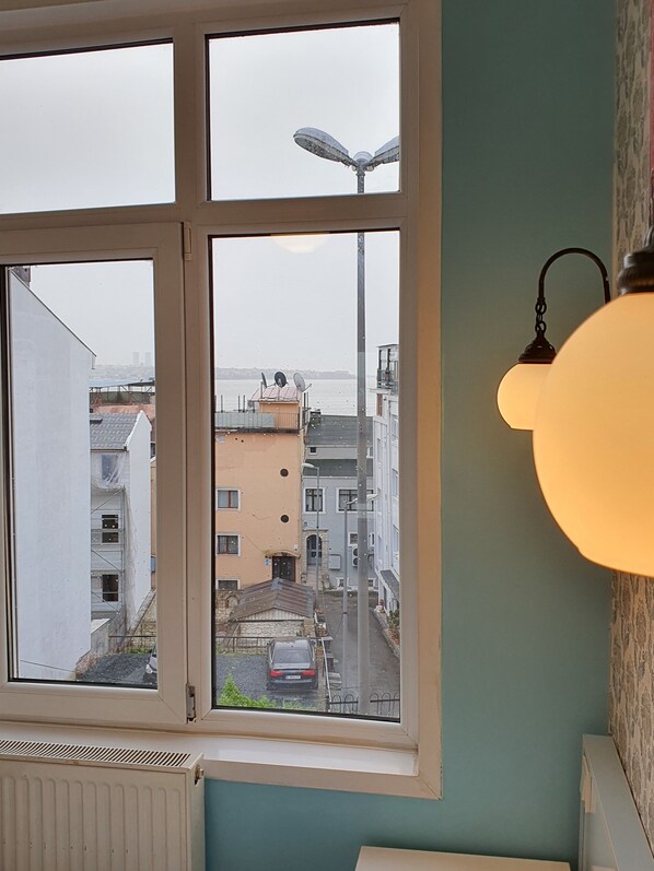 Habitación con un gran ventanal que da a una vista panorámica de la ciudad, un radiador y una lámpara colgante.