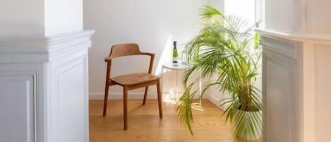 Un pasillo con suelo de madera, una silla de madera y una planta en maceta.