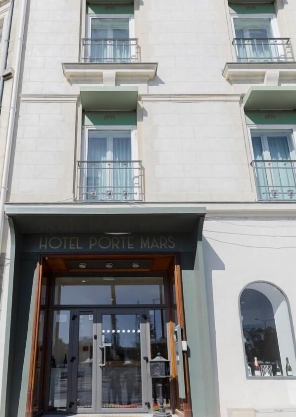L’entrée d’un hôtel, avec une enseigne indiquant « HÔTEL PORTE MARS ».