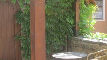 A wooden door, a stone wall, and a round table with wicker chairs.