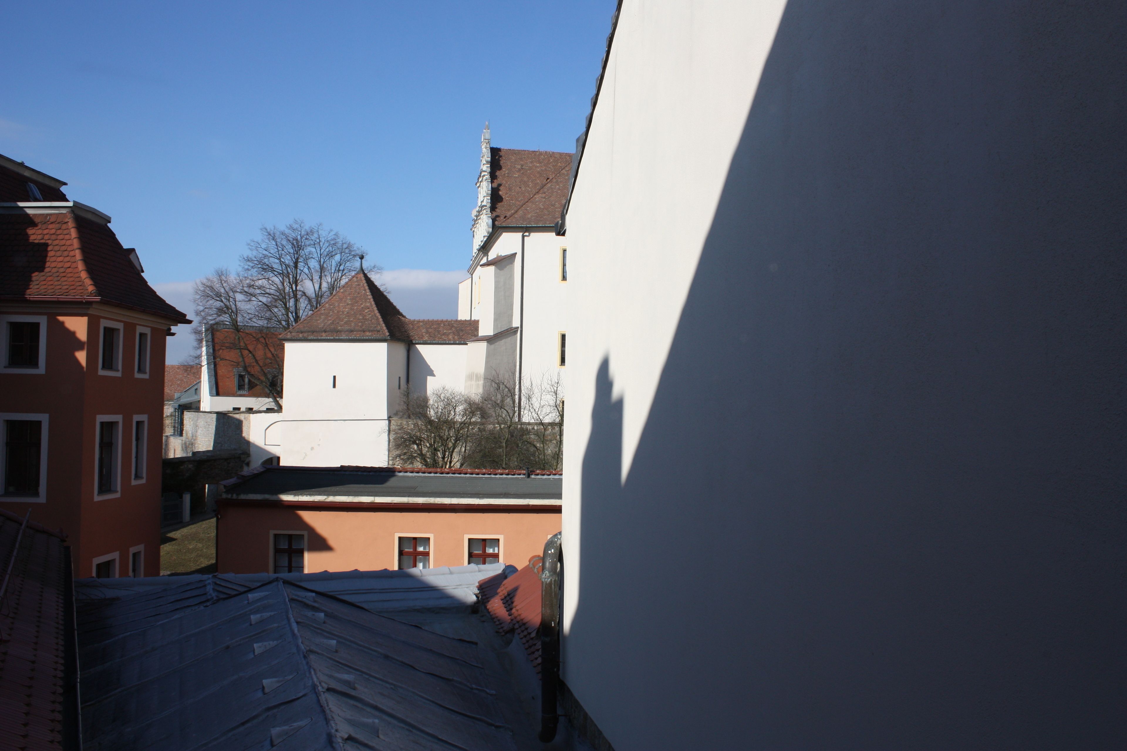 Un estrecho callejón entre edificios con tejados inclinados y un cielo azul despejado.