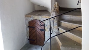 A staircase with a wooden door at the bottom, a stone wall, and a metal railing.