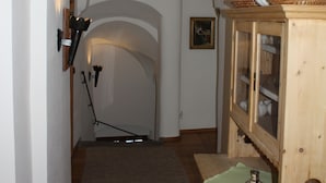 A narrow hallway with an arched ceiling, a wooden cabinet with glass doors, and a carpeted floor.