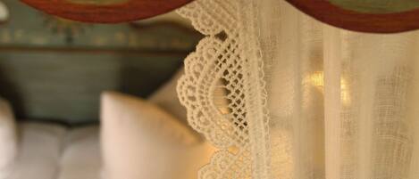 Detalle de un cortinero blanco de encaje con adornos de madera.
