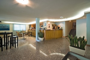 A spacious lobby with a reception desk, seating area, and a staircase. - Parador Hotel Residence (Cesenatico)